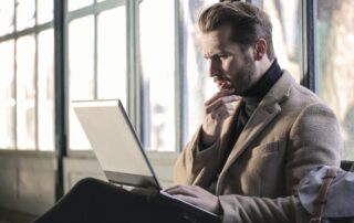 Man sitting with laptop and a confused look on his face